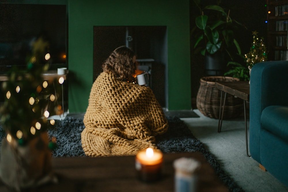 a woman wrapped in a blanket sitting on a rug in a living room