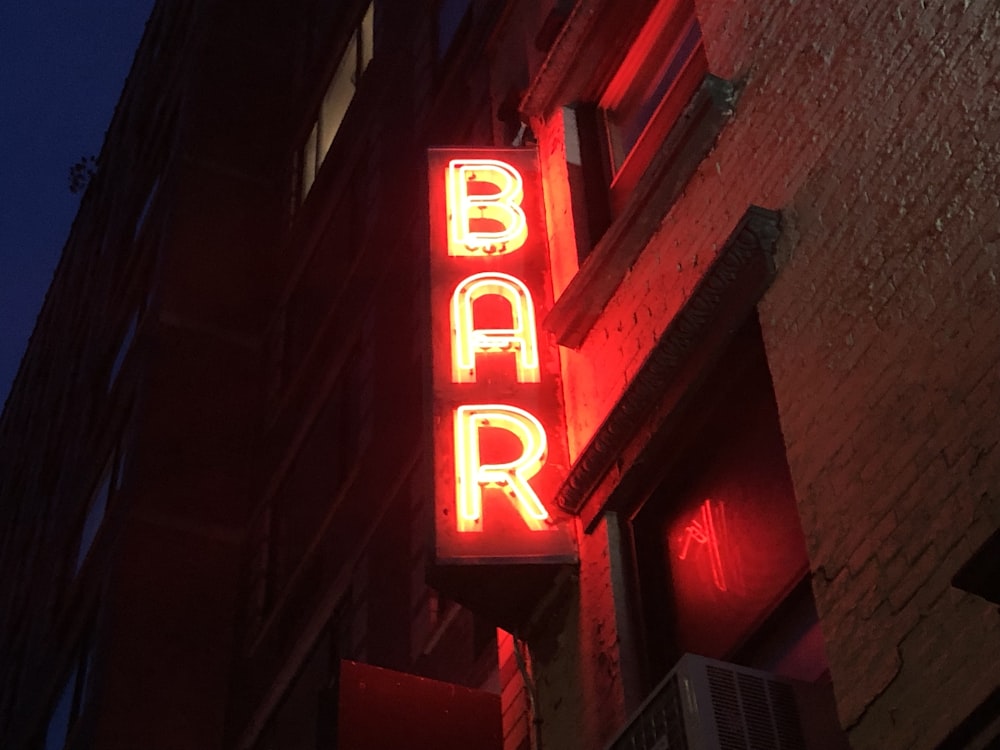 Un'insegna al neon che legge bar sul lato di un edificio