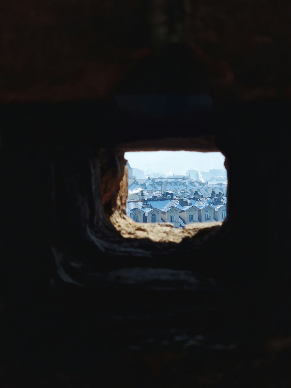 a view of a city through a hole in a wall