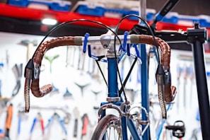 Close-up of a handcrafted, axle-less bicycle frame with brass accents in a warm workshop setting