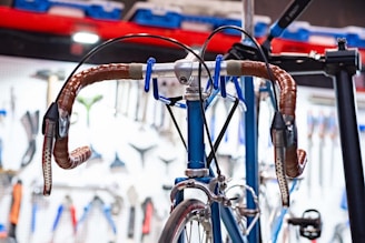 Close-up of a handcrafted, axle-less bicycle frame with brass accents in a warm workshop setting