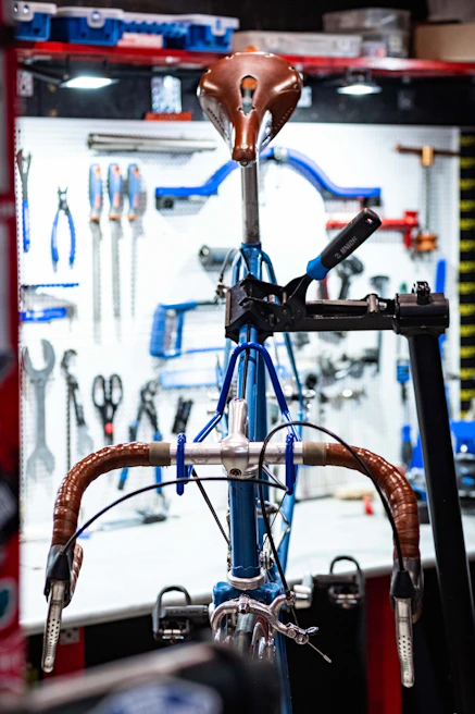 A sleek road bike being carefully inspected on a repair stand in a clean workshop