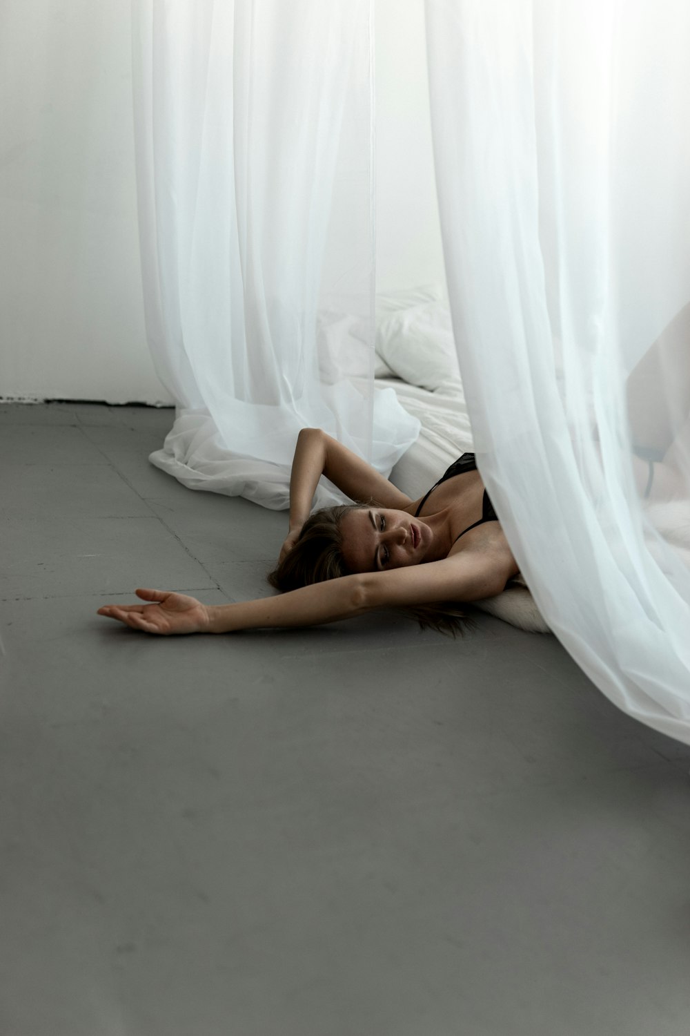 a woman laying on the floor in front of a white curtain
