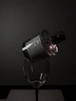 An elegant evening setting with candles and a bottle of perfume on a polished black table.