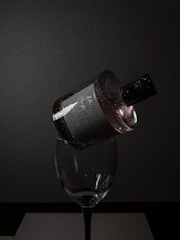 Close-up CGI render of an elegant perfume bottle with reflective glass and metallic details, set against a moody dark background.