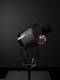 A moody image of a perfume bottle resting on dark burgundy velvet, gently catching flickers of ambient light.