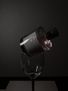 A moody, cinematic close-up of a perfume bottle resting on dark velvet with soft golden light highlighting its contours.