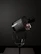 Elegant lifestyle shot of a perfume bottle beside a softly glowing candle in a dark room.
