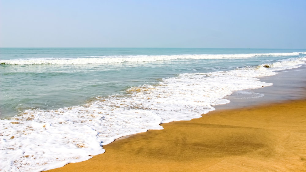 a sandy beach with waves coming in to shore