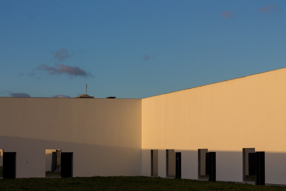 a white building with black shutters and a sky background