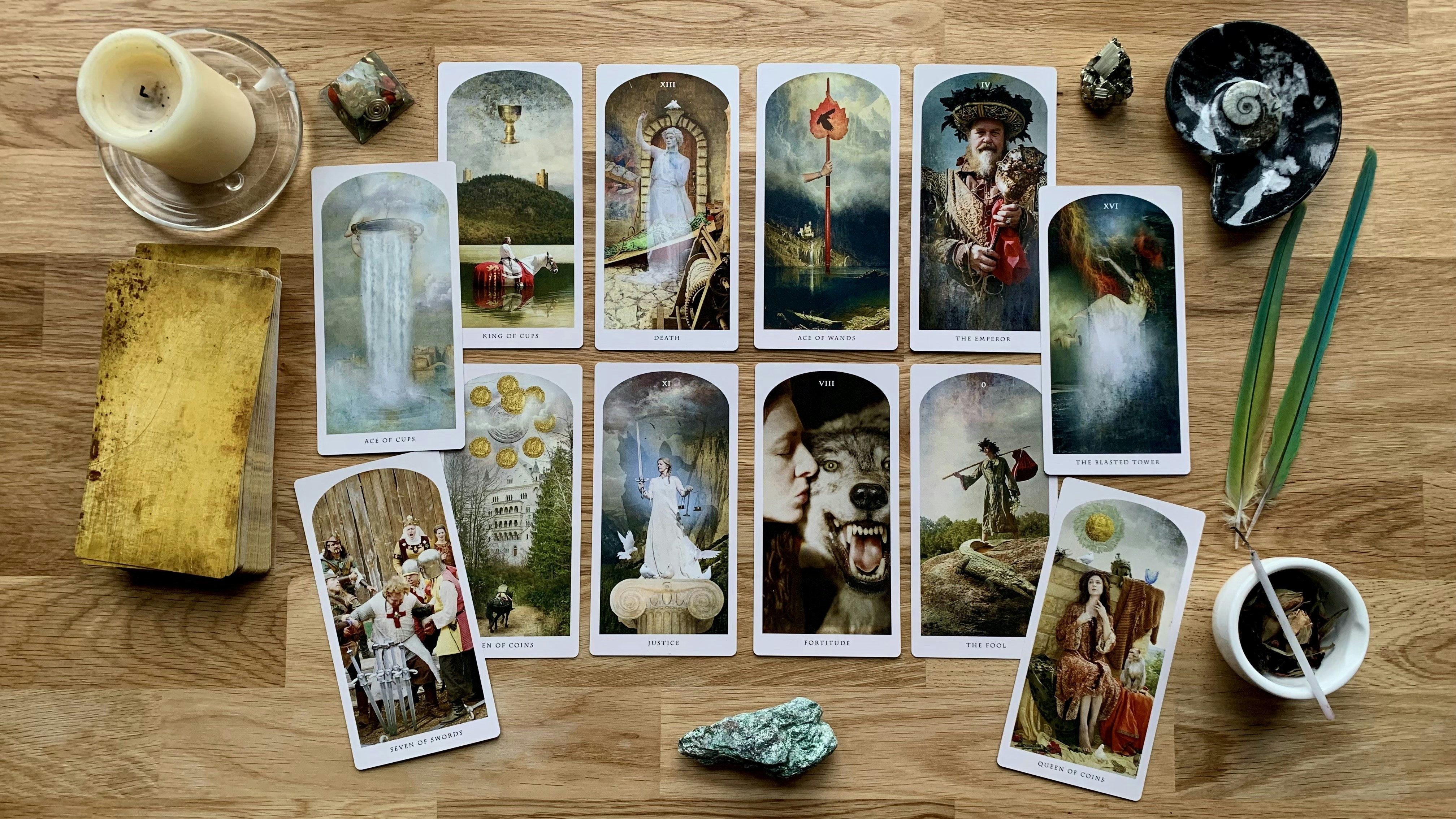 Cartas de tarô abertas sobre mesa de madeira com velas e cristais ao redor, luz íntima e dourada