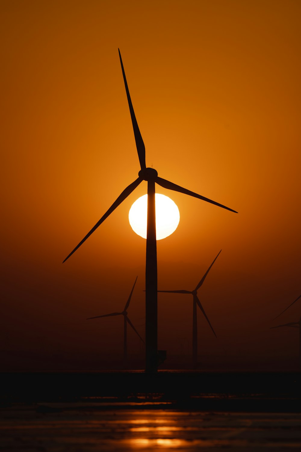 a group of windmills are silhouetted against a sunset