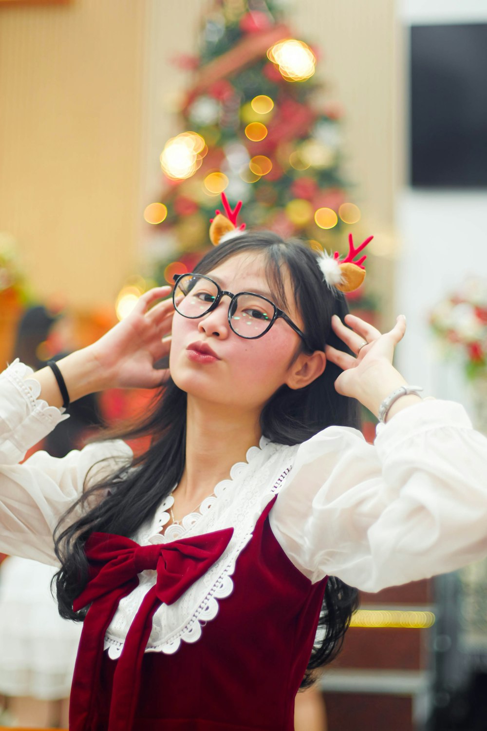 a woman in a red and white dress with a christmas tree in the background