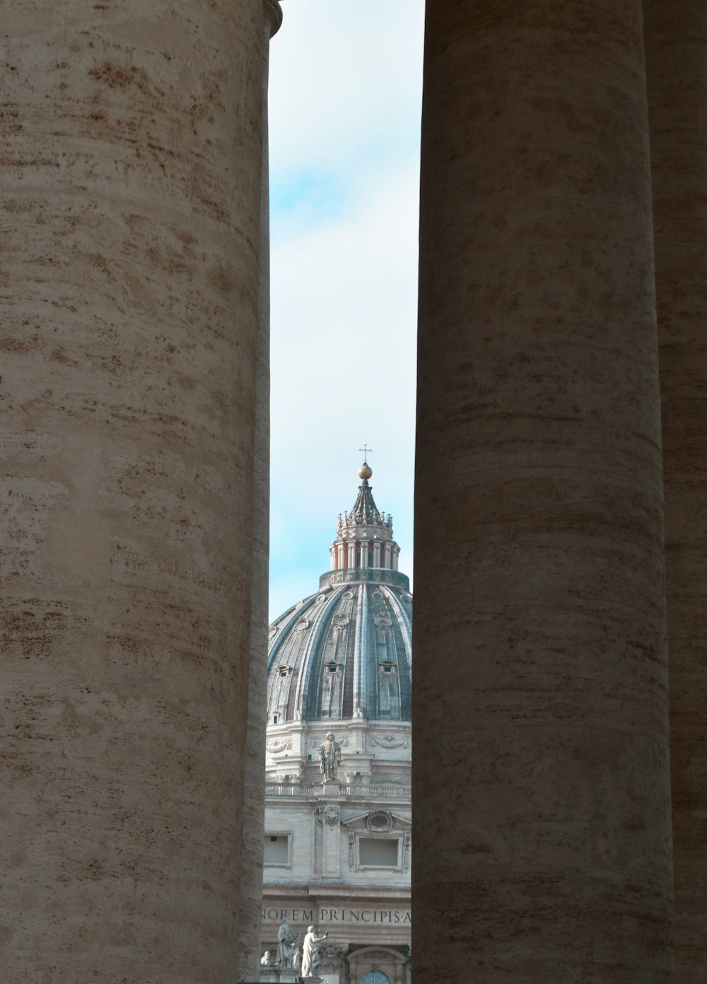 a view of the dome of a building from between two pillars