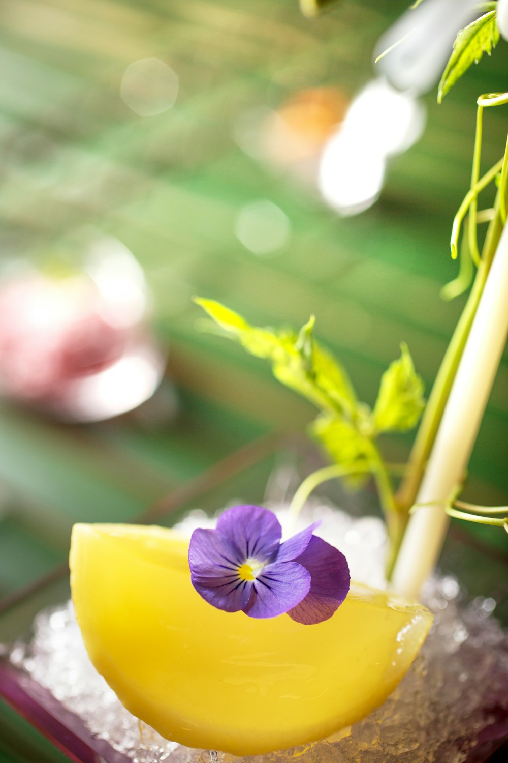 a yellow vase with a purple flower in it