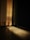 Curtains gently illuminated by sunlight, casting a warm glow on the floor. The light highlights the textured pattern of the fabric and creates a contrast between the bright and shadowed areas.