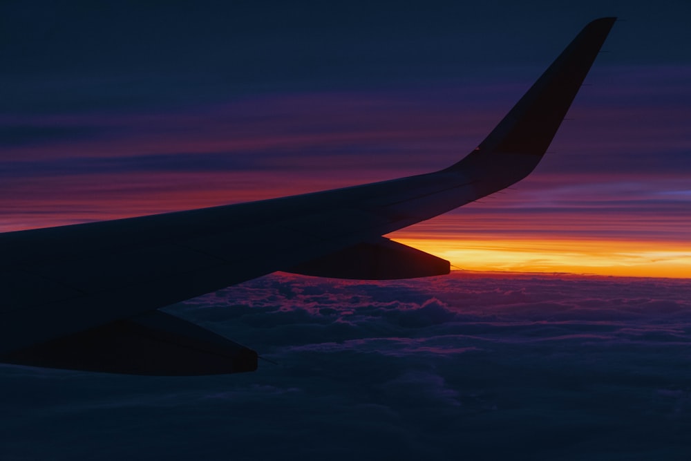 a view of the wing of an airplane at sunset