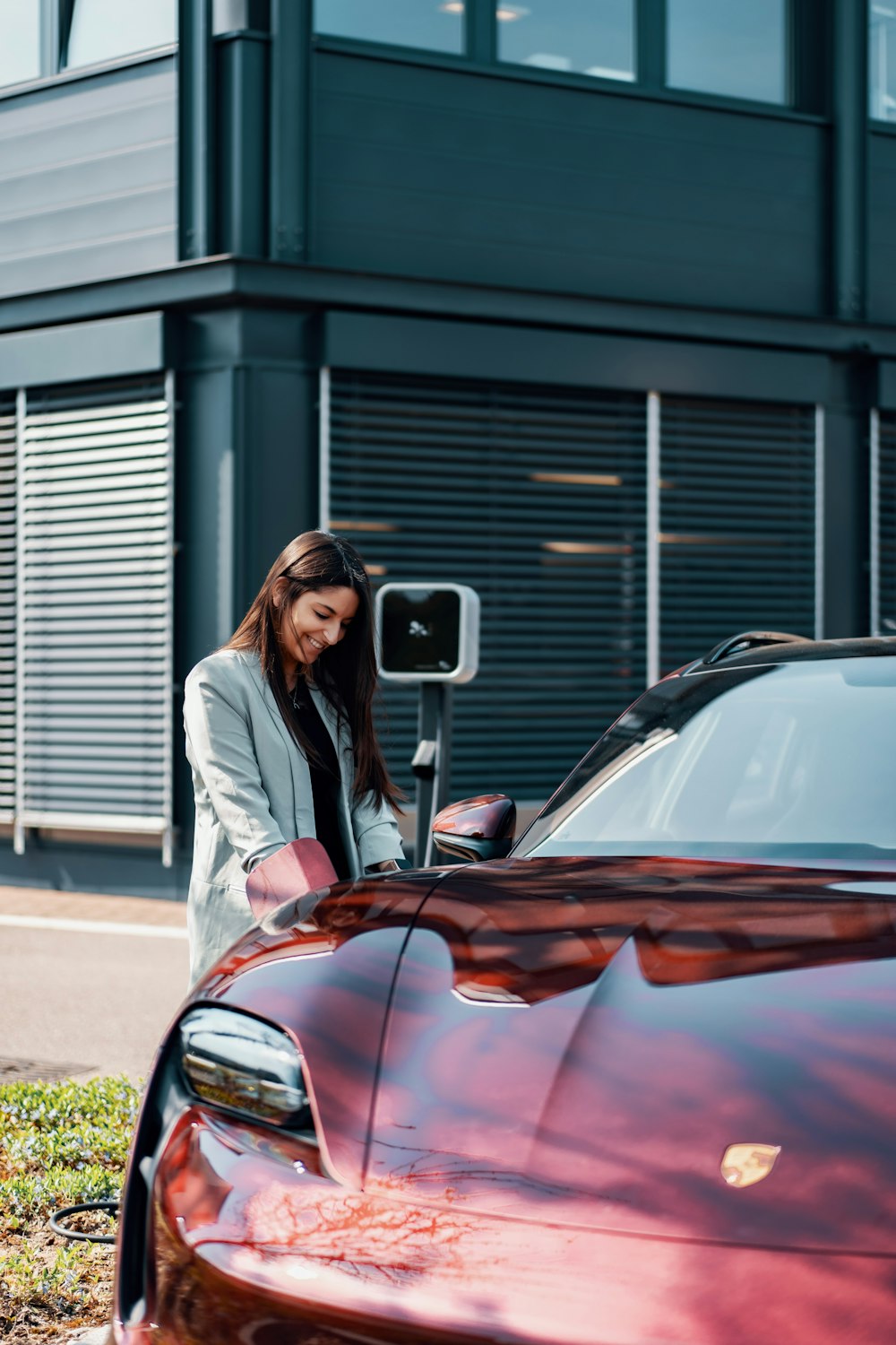 a woman standing next to a red car