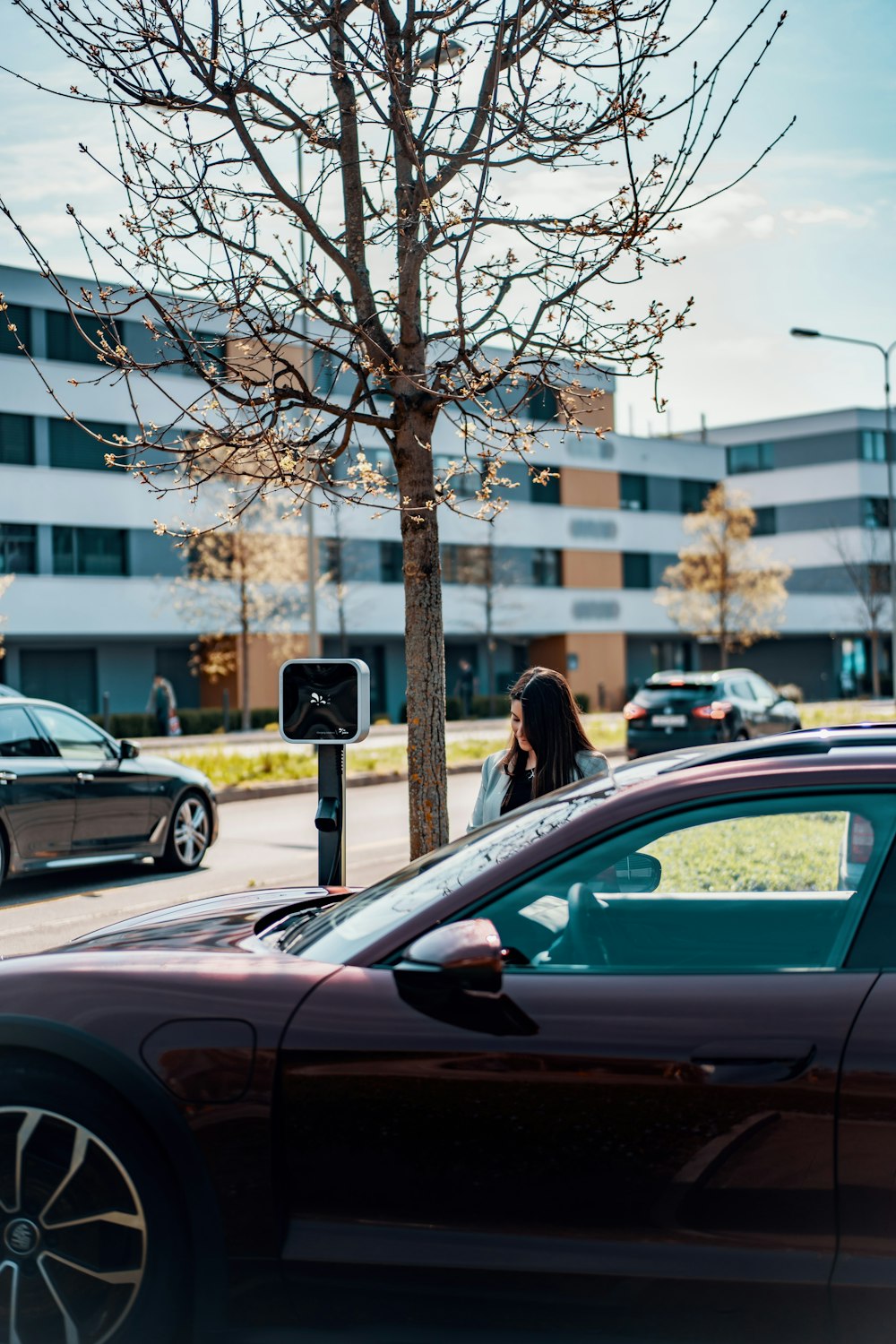 a woman standing next to a car talking on a cell phone