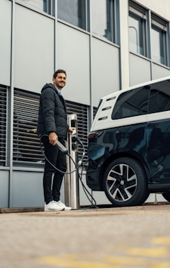 A friendly technician in a branded 'the ev wizard' uniform working on an electric vehicle outdoors.