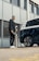 A happy customer standing next to their electric vehicle and charger.