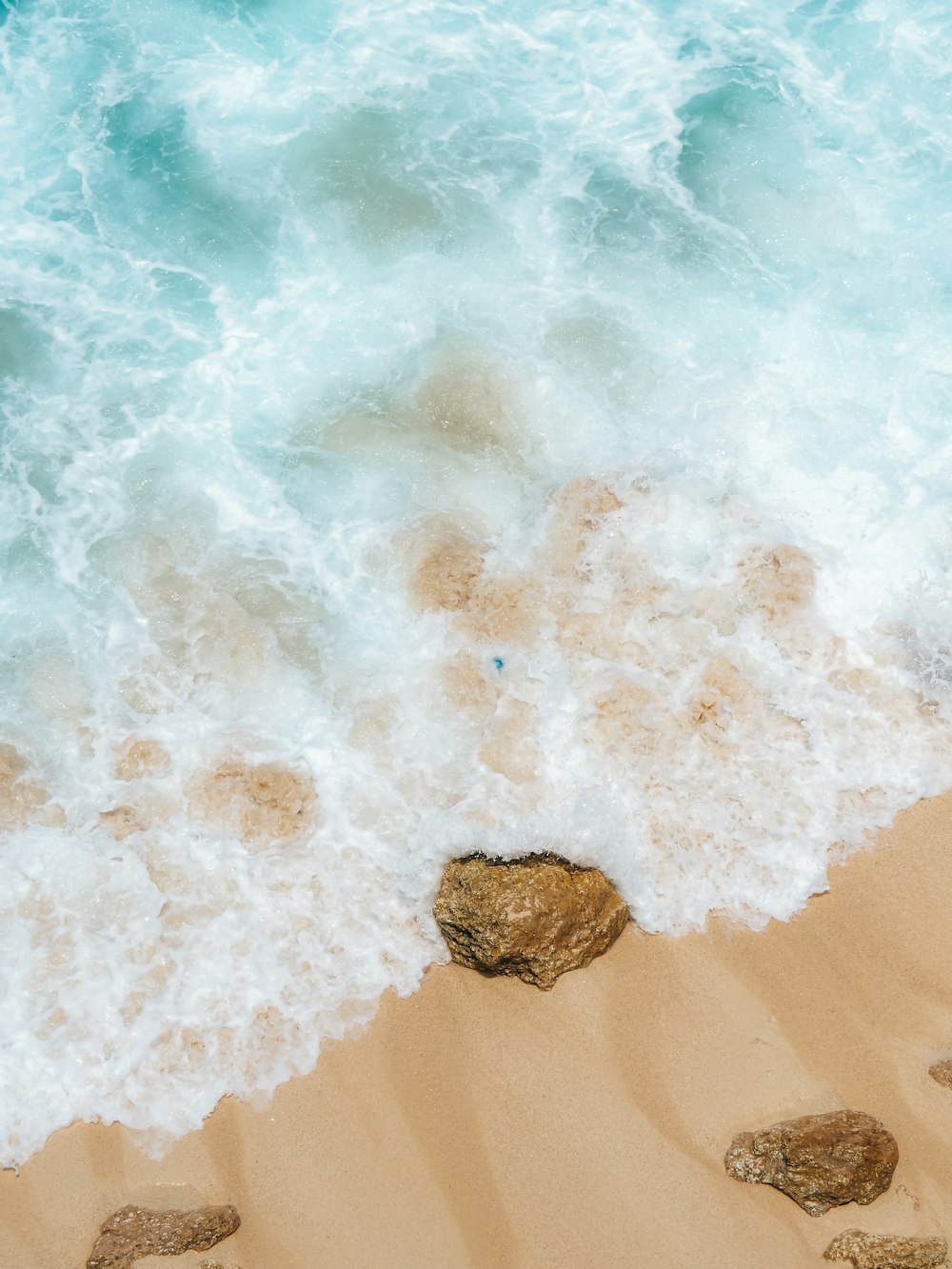 a couple of rocks sitting on top of a sandy beach