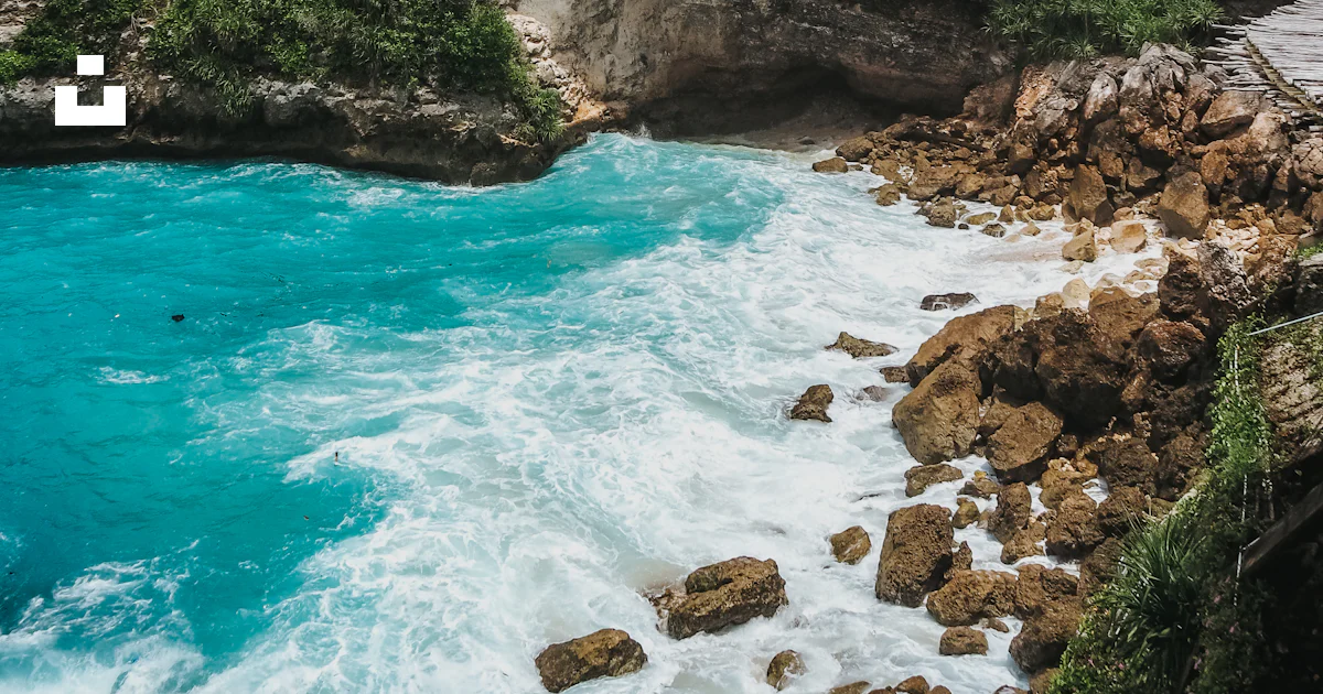 Playa Rocosa Rd Foto Una playa rocosa con agua azul y árboles verdes – Imagen Indonesia ...