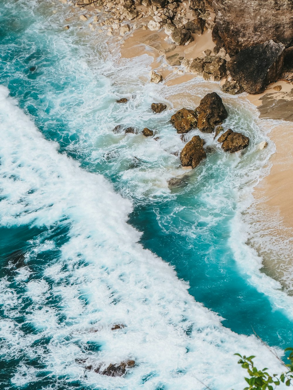 an aerial view of a beach with waves and rocks