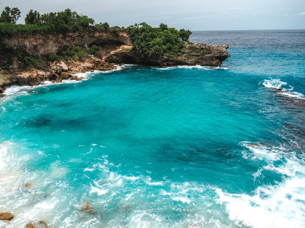 an aerial view of a blue ocean with a cliff in the background