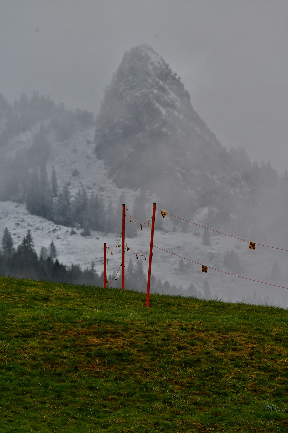 a foggy mountain with a red fence in the foreground