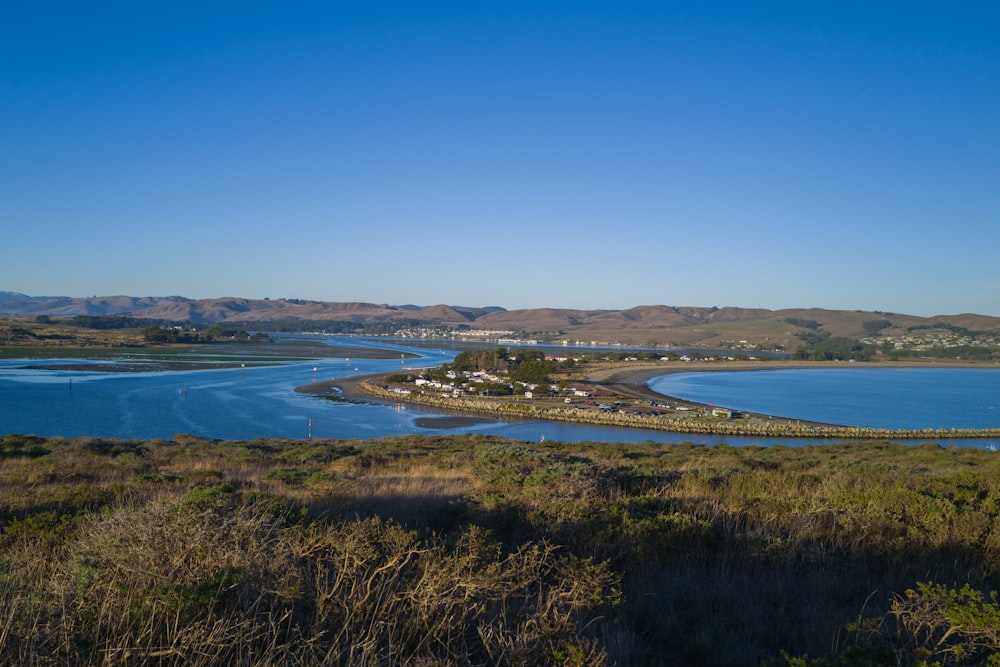 a body of water surrounded by a lush green field