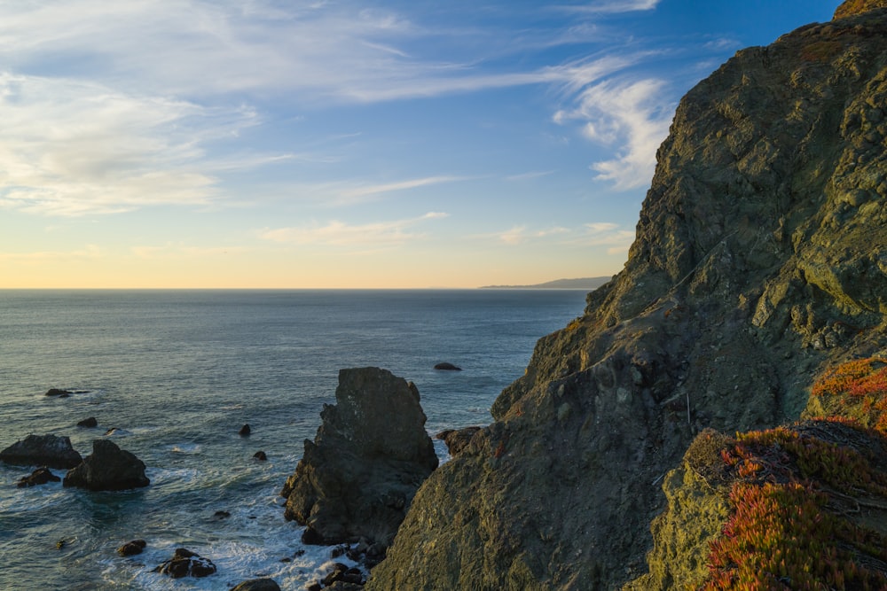 Une falaise rocheuse surplombe l’océan au coucher du soleil