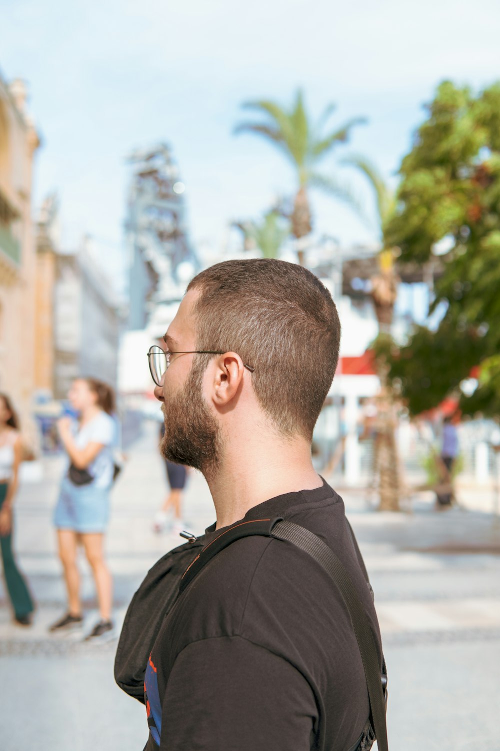 Un uomo con barba e occhiali in piedi su una strada