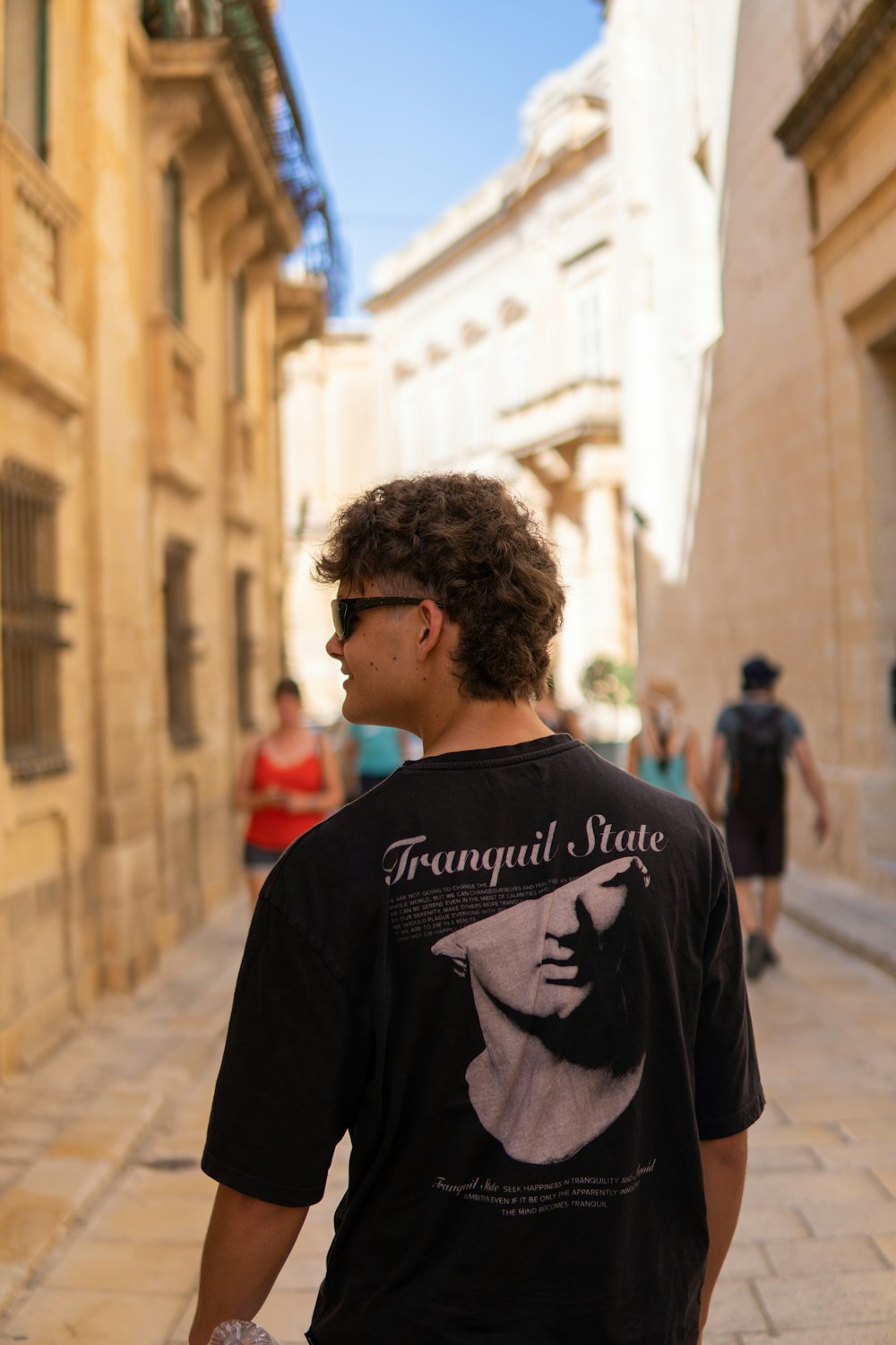 a man walking down a street next to tall buildings