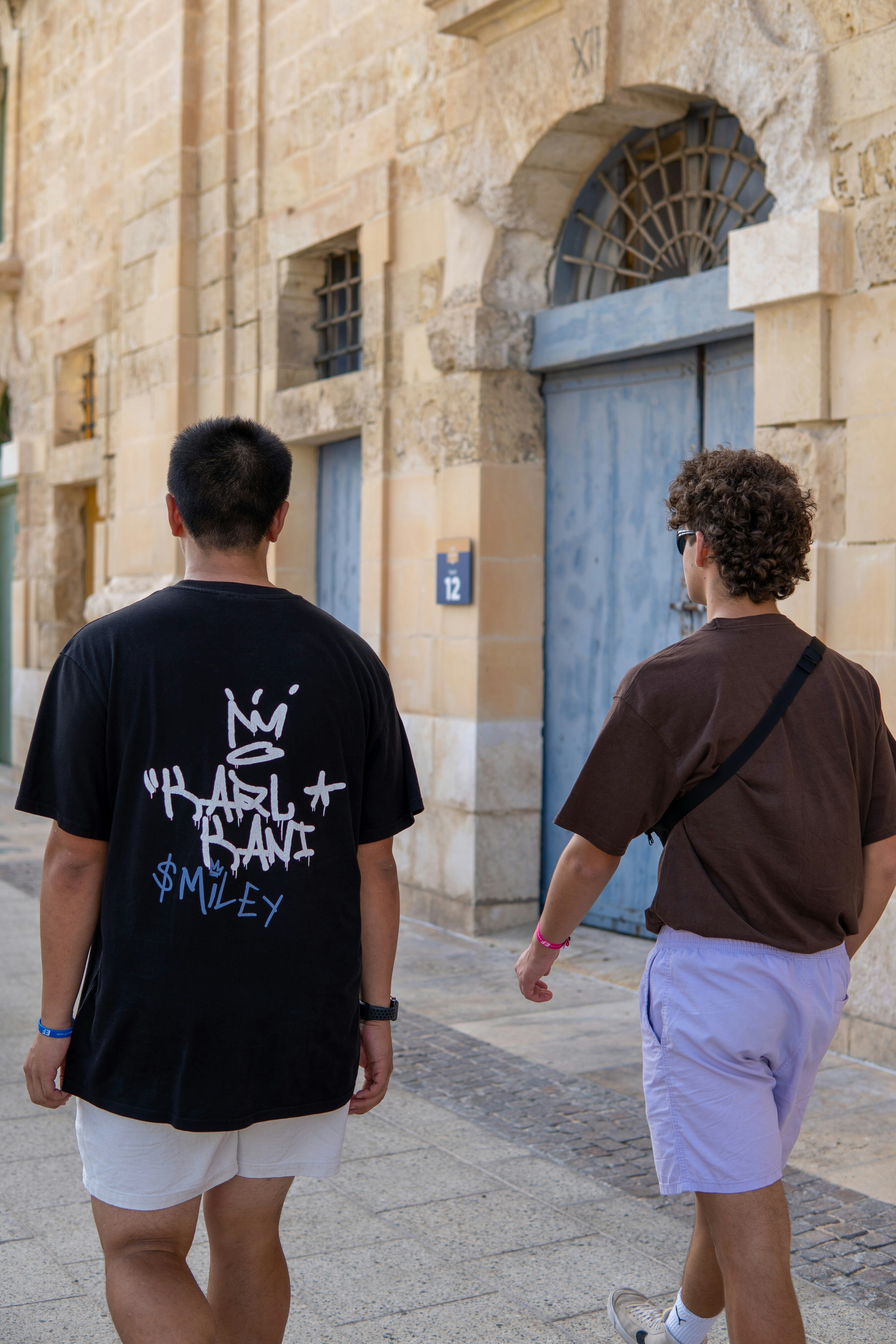 Two men walking down a sidewalk in front of a building photo – Free ...