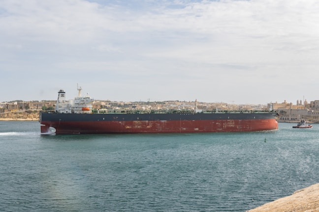 Close-up of loading hoses connected to a tanker ship with ocean in the background.