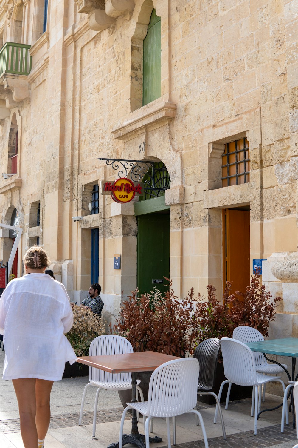 a woman walking down a street past tables and chairs