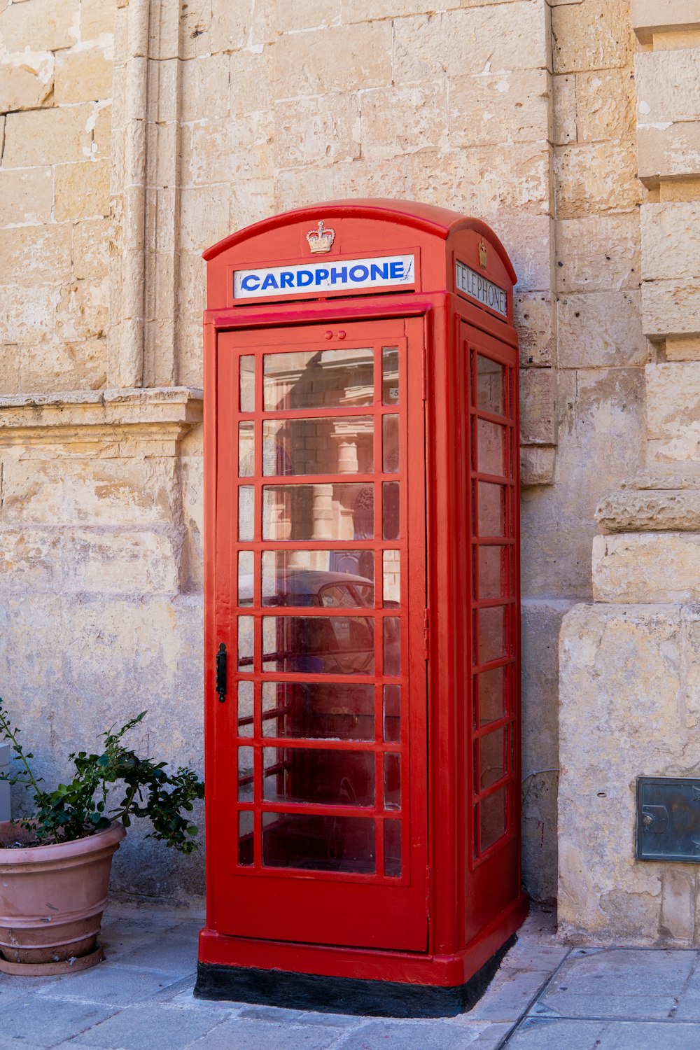 a red phone booth sitting on the side of a building