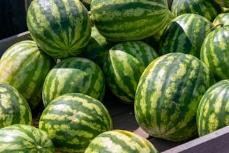 Close-up of ripe, juicy watermelons stacked neatly in a rustic wooden crate.