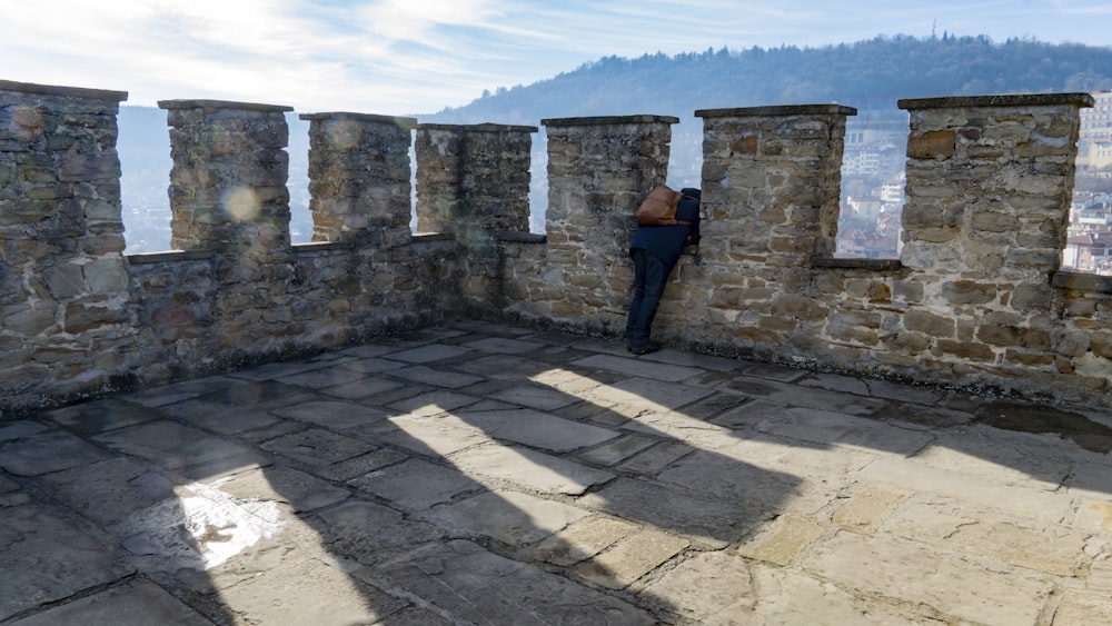 a person leaning against a stone wall