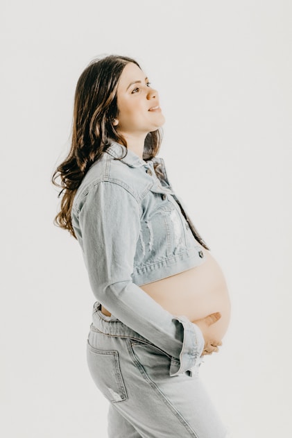 a pregnant woman wearing a jean jacket and jeans