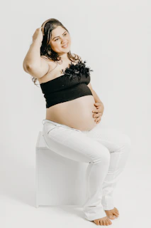 a pregnant woman sitting on top of a white chair