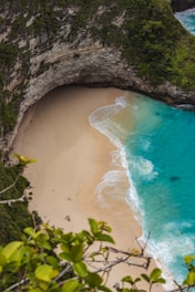 A pristine, hidden beach with turquoise water framed by rugged cliffs and soft white sand.