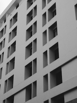 A sleek black-and-white photo of a modern commercial building equipped with access control fob readers.