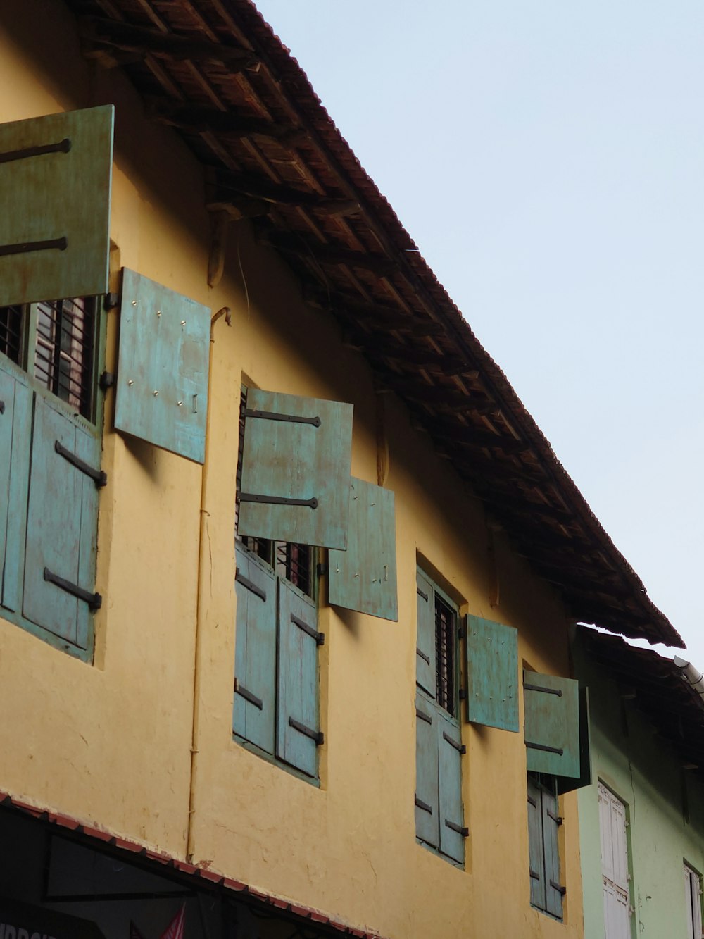 a yellow building with blue shutters and a brown roof