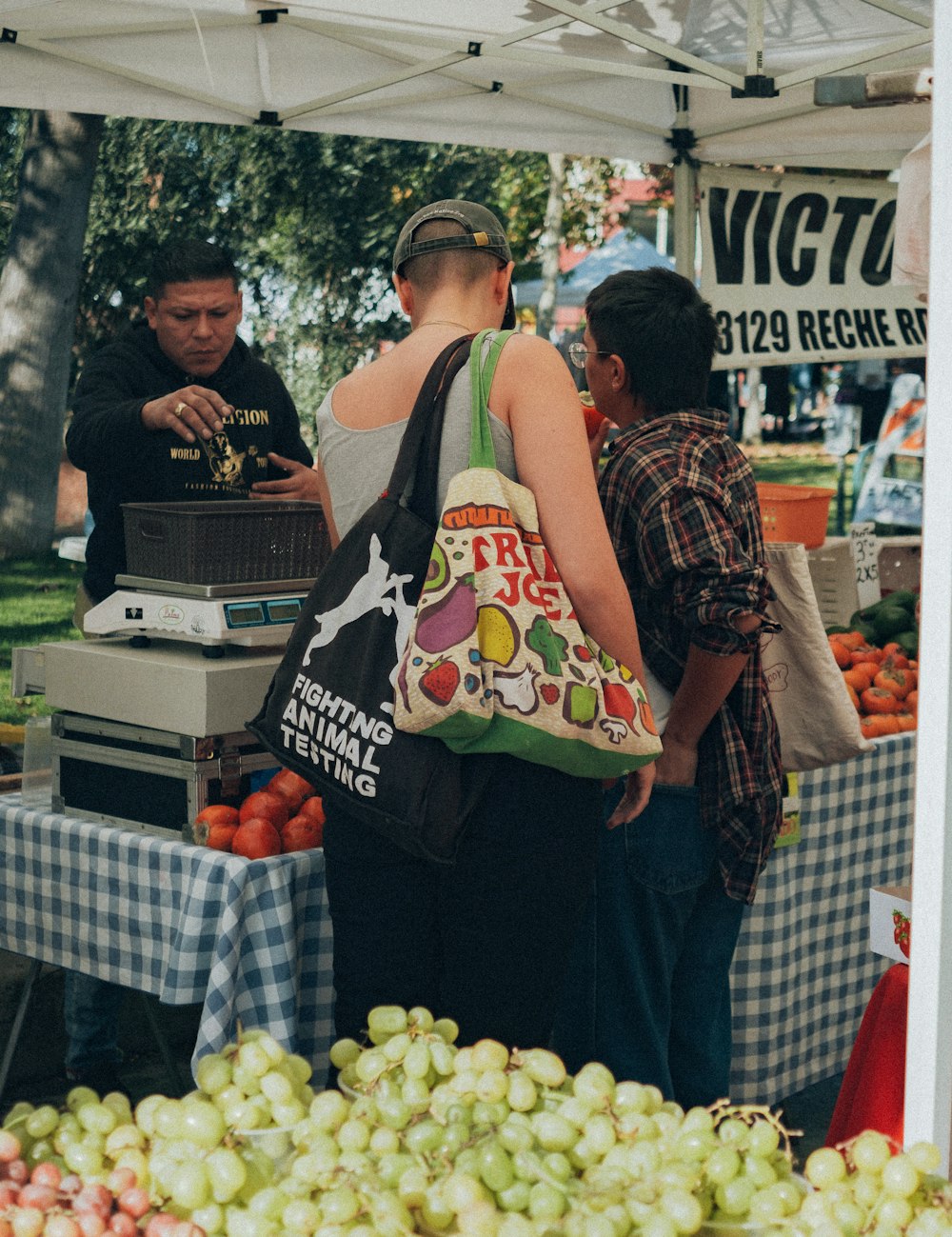 a group of people standing around a fruit stand