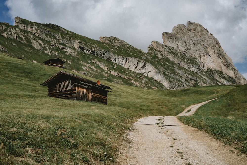 a dirt road leading to a wooden cabin in the mountains