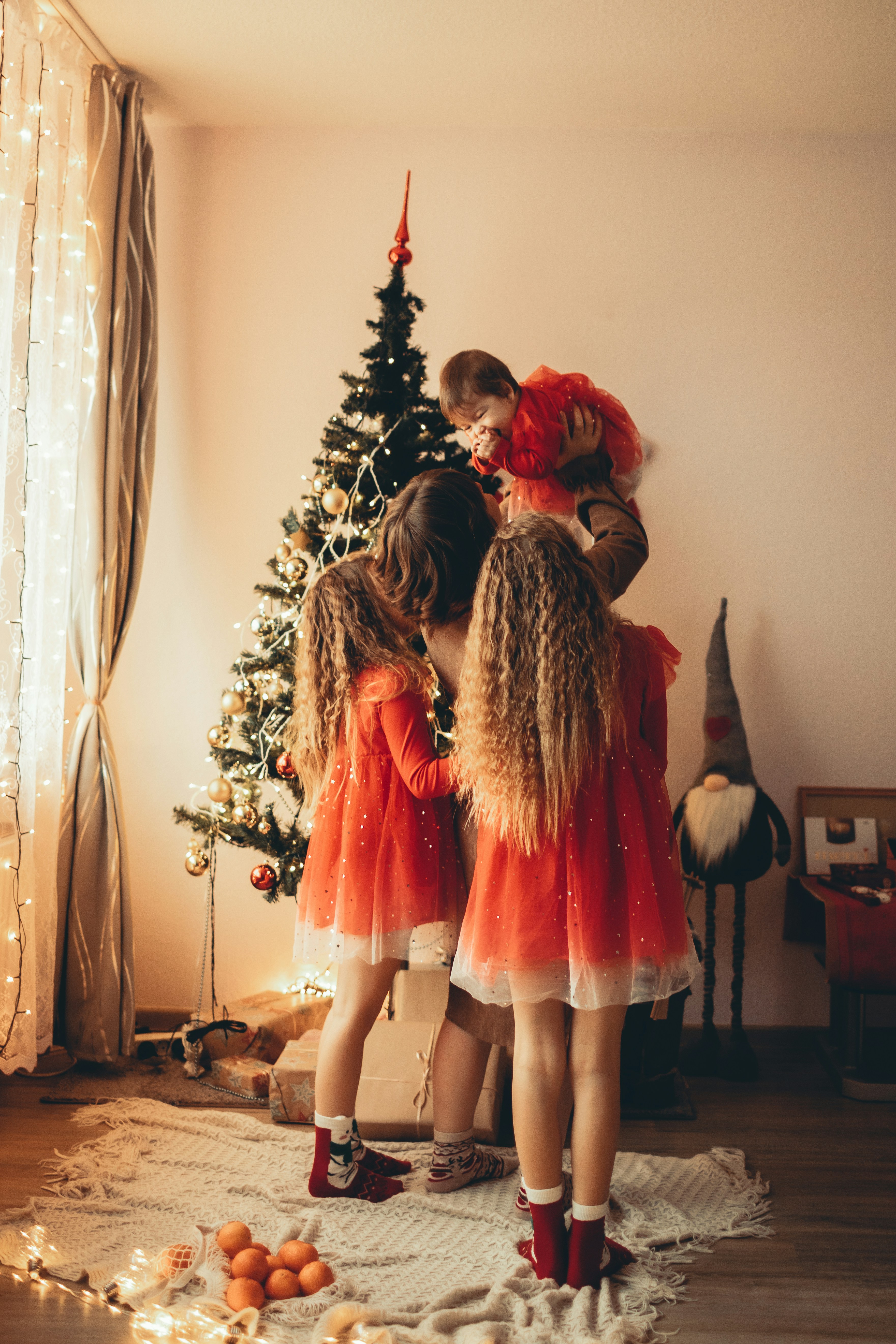 a group of young girls standing next to a christmas tree