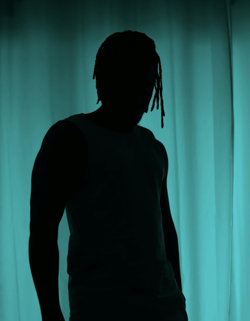a man with dreadlocks standing in front of a curtain