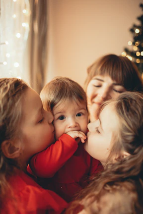 Katherine smiling warmly while holding her triplets in a cozy home setting.